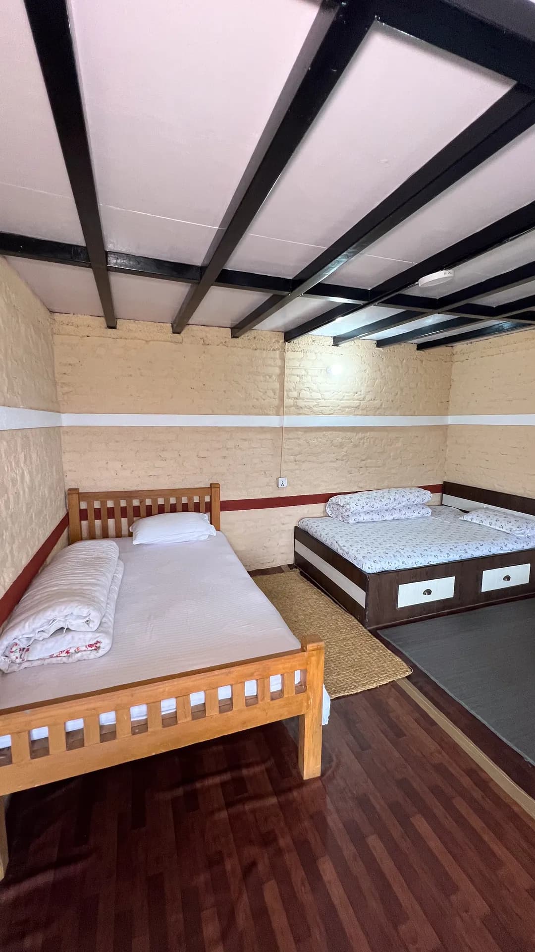 Clean twin or triple sharing guest room with wooden beds at Baseri Farm Stay